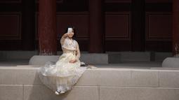 Seorang wanita mengenakan pakaian tradisional Korea, Hanbok sambil berswafoto di istana Gyeongbokgung, Seoul, Rabu (26/9). Korea Selatan sedang menikmati hari terakhir dari liburan Chuseok atau Hari Thanksgiving. (AFP PHOTO / Ed JONES)