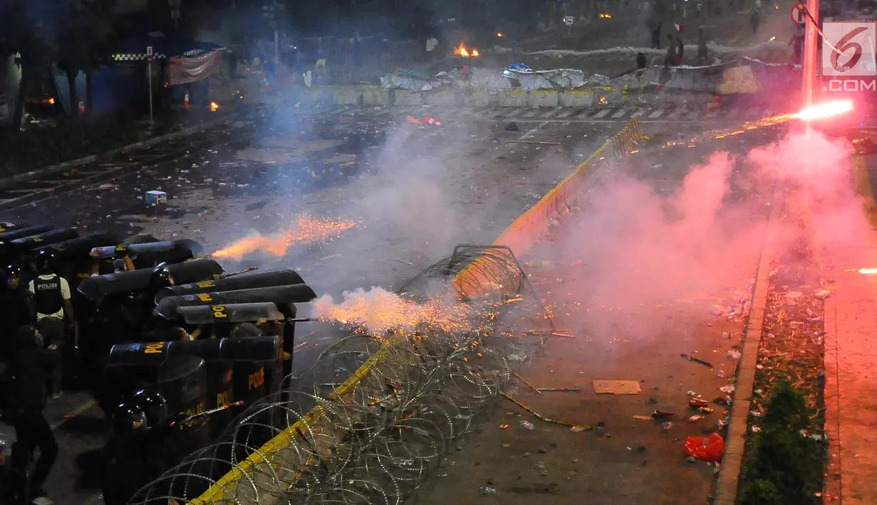 Petugas kepolisian menghalau tembakan kembang api saat bentrokan dengan massa aksi 22 Mei di sekitar depan gedung Bawaslu, Jalan MH Thamrin, Jakarta, Rabu (22/5/2019). Aksi unjuk rasa itu dilakukan menyikapi putusan hasil rekapitulasi nasional Pemilu serentak 2019. (Liputan6.com/Angga Yuniar)
