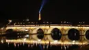 Pandangan umum Menara Eiffel yang diterangi dan jembatan Pont Neuf tercermin di sungai Seine pada malam hari selama penerapan lockdown atau penguncian wilayah di Paris, 23 April 2020. Pandemi corona COVID-19 membuat Prancis menerapkan lockdown. (Ludovic MARIN / AFP)