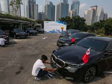 Petugas membersihkan mobil BMW i7 dan i5 di komplek GBK, Senayan, Jakarta, Jumat (3/5/2024). (Liputan6.com/Angga Yuniar)