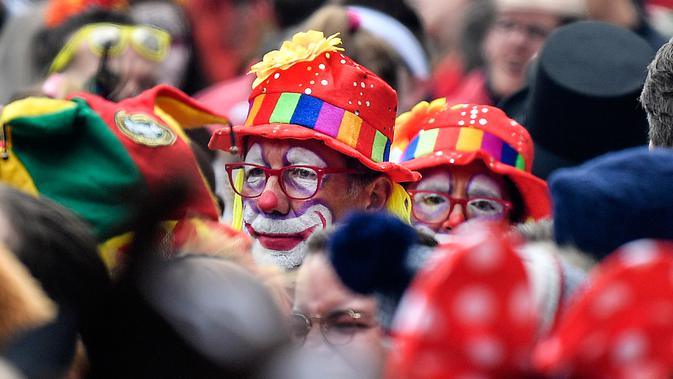Dua badut mencoba melintas di mana puluhan ribu orang bersuka ria merayakan dimulainya musim karnaval di jalan-jalan Kota Cologne, Jerman, Senin (11/11/2019). Tradisi ini akan dimulai tepat pada jam 11.11, tanggal 11, dan bulan sebelas. (AP Photo/Martin Meissner)