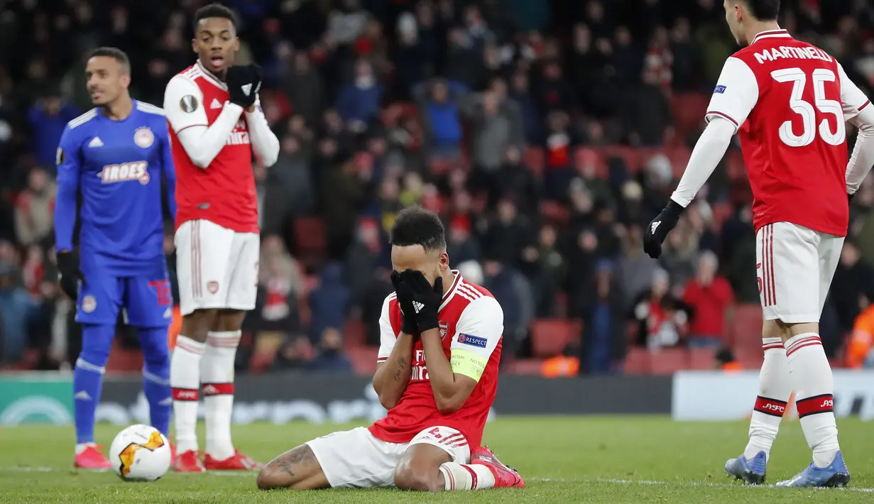 Penyerang Arsenal, Pierre-Emerick Aubameyang (tengah) menutup wajahnya usai pertandingan melawan Olympiakos pada leg kedua babak 32 besar Liga Europa di stadion Emirates, London, Kamis (27/2/2020).  Olympiakos menang 2-1 dan lolos dengan unggul agregat gol tandang 2-2. (AP Photo/Frank Augstein)