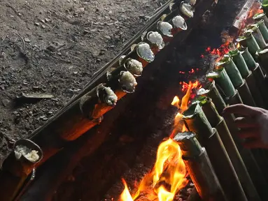 Pekerja membakar lemang di kawasan Kwitang, Jakarta, Minggu (9/3/2025). (Liputan6.com/Herman Zakharia)