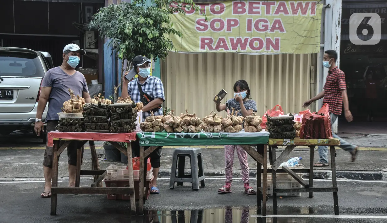 Pedagang melayani pembeli ketupat matang di jalan kawasan Rawamangun, Jakarta, Senin (19/7/2021). Pedagang membanderol ketupat siap santap tersebut mulai dari harga Rp30 ribu hingga Rp40 ribu per ikat (10 buah) tergantung besar kecil ukuran. (merdeka.com/Iqbal S. Nugroho)