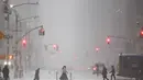 Badai menyebabkan ribuan penerbangan dibatalkan hingga pemadaman listrik besar-besaran. Tampak dalam foto, orang-orang berjalan melintasi Sixth Avenue saat salju turun di distrik Manhattan, Kota New York, pada Minggu 25 Januari 2026. (CHARLY TRIBALLEAU/AFP)