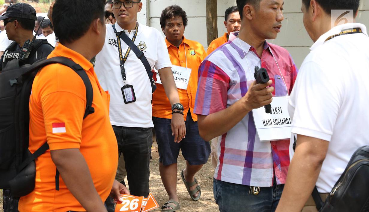 Tersangka IAW menjalani proses rekonstruksi Lapangan Tembak Senayan, Jakarta, Jumat (19/10). IAW menjalani 25 adegan rekonstruksi terkait dugaan enam peluru yang tertembak ke enam ruangan di Gedung DPR RI. (Liputan6.com/Immanuel Antonius)