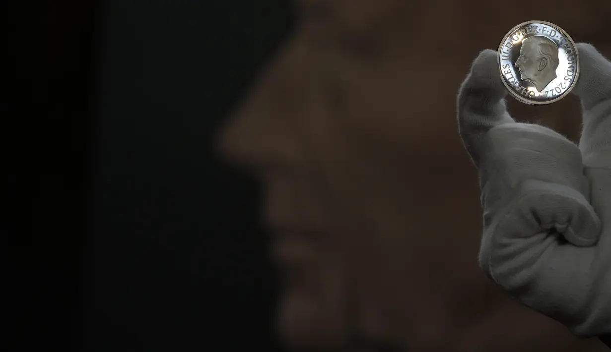 Seorang staf dari Royal Mint mengangkat koin lima pound bergambar Raja Charles III, yang akan menjadi salah satu koin pertama yang menyandang kepala raja baru, selama pratinjau pers di London, Kamis, 29 September 2022. Koin bergambar Raja Charles III terlihat pada pecahan 50 pence, yang akan mulai beredar dalam beberapa bulan mendatang. (AP Photo/Alastair Grant)