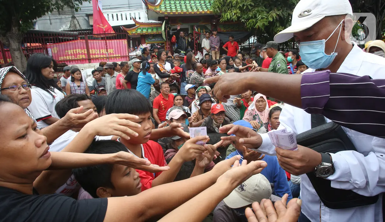 Pengemis berebut angpao yang dibagikan di halaman Vihara Dharma Bhakti, Petak Sembilan, Jakarta Barat, Sabtu (25/1/2020). Pembagian Angpao tersebut dalam rangka berbagi dengan sesama ketika perayaaan Tahun Baru Imlek 2571. (Liputan6.com/Angga Yuniar)