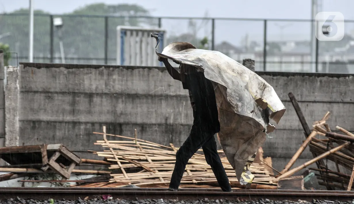 Warga berjalan melewati rel pascapenggusuran ratusan bangunan semipermanen di Kampung Bambu, Tanjung Priok, Jakarta Utara, Selasa (11/10/2022). PT KAI membongkar sekitar 254 bangunan semipermanen yang berada di bantaran rel atau dekat Jakarta International Stadium (JIS) guna sterilisasi jalur kereta api dan pembangunan stasiun baru di kawasan tersebut. (merdeka.com/Iqbal S. Nugroho)
