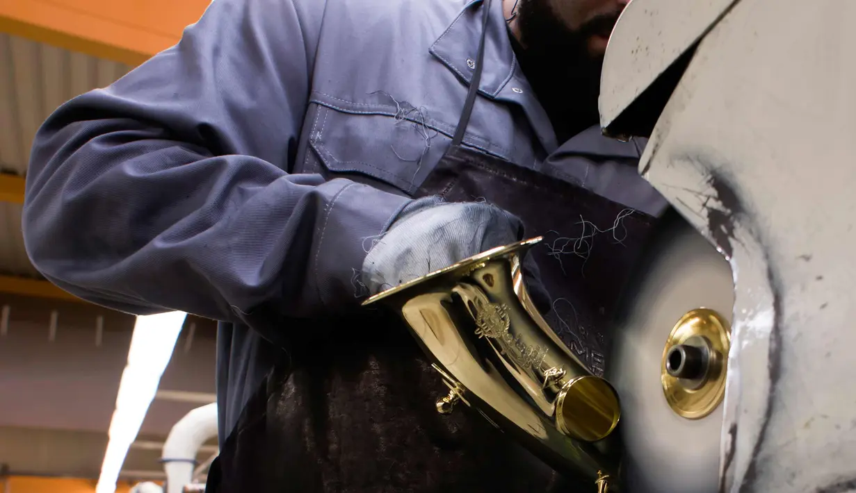 Pekerja membersihkan bagian body alat musik saksofon di pabrik Selmer Saxophone di Mantes-la-Ville, Prancis (17/1). Saksofon biasanya terbuat dari logam dan dimainkan menggunakan single-reed seperti klarinet. Saksofon. (AFP Photo/Alain Jocard)