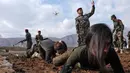Pasukan perempuan Peshmerga merayap di tanah saat berlatihan dalam upacara kelulusan di Kota Soran, Irak, Rabu (12/2/2020). Latihan militer pasukan bersenjata Kurdi tersebut dilakukan sekitar 100 kilometer timur laut ibu kota otonomi wilayah Kurdi di Irak, Arbil. (SAFIN HAMED/AFP)