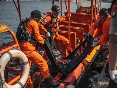 Petugas Basarnas menurunkan kantung jenazah dan serpihan pesawat Lion Air JT 610 di Posko Evakuasi, Tanjung Priok, Jakarta, Senin (29/10). Pesawat Lion Air JT 610 dipastikan jatuh di laut utara Karawang. (Liputan6.com/Faizal Fanani)