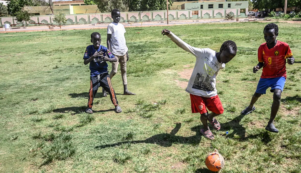 Seorang anak menggiring bola saat berman sepak bola di Khartoum (23/4). Khartoum yang merupakan pusat politik, kebudayaan, dan perdagangan. (AFP Photo/Ozan Kose)