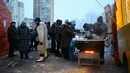 Terdampak pemadaman listrik dan air, warga Kyiv terlihat mengantre untuk mendapatkan makanan hangat di tengah kondisi musim dingin yang ekstrem. Tampak dalam foto, para sukarelawan dari organisasi amal makanan yang berbasis di Amerika Serikat (AS), World Central Kitchen, membagikan makanan hangat kepada warga setempat di sebuah kawasan perumahan di Kyiv yang mengalami pemadaman listrik dan air akibat serangan Rusia yang menghantam sektor energi, Kamis 22 Januari 2026. (Sergei GAPON/AFP)