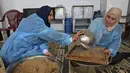 Para wanita membuat maftoul atau couscous di Khan Yunis, Jalur Gaza, Palestina, 10 Januari 2022. Maftoul dibentuk seperti granula-granula dan dikukus dalam mangkuk khusus. (SAID KHATIB/AFP)