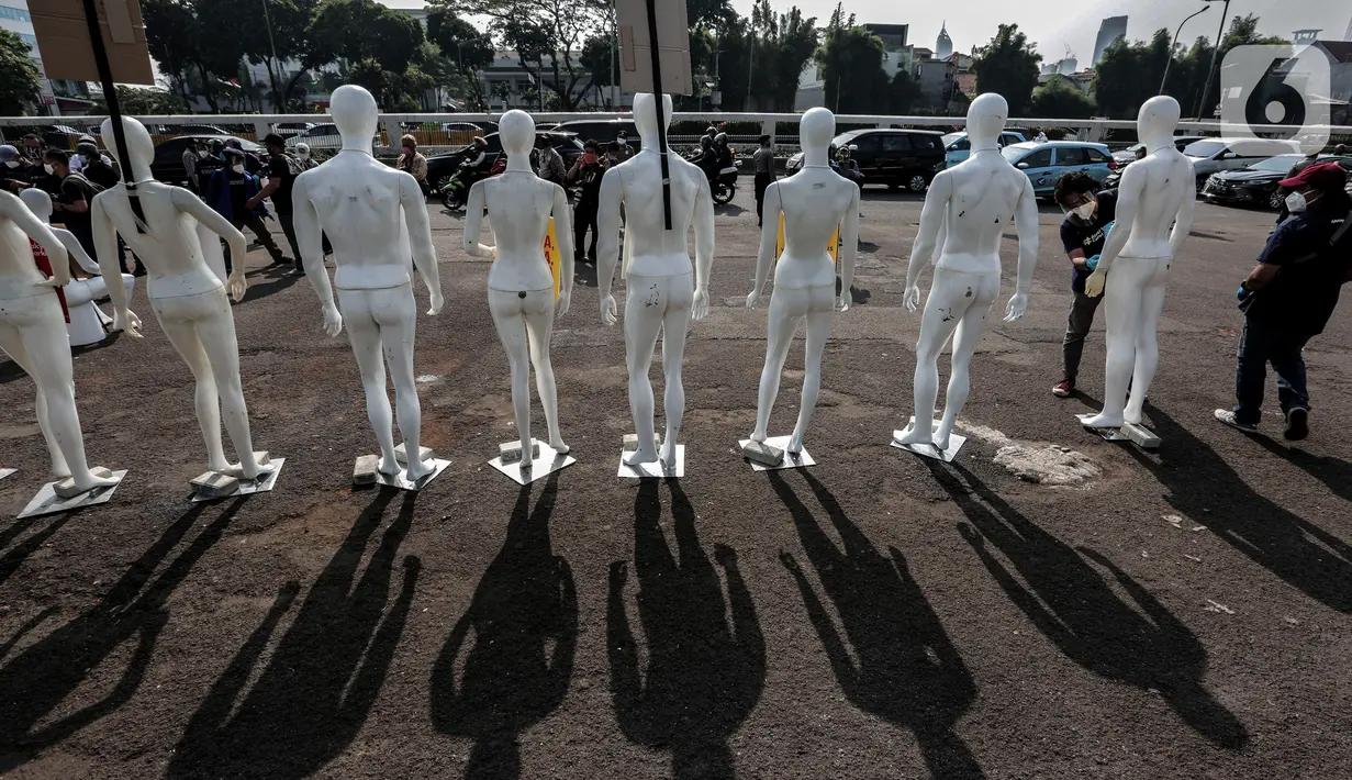 Aktivis Greenpeace Indonesia menata puluhan maneken saat menggelar aksi damai di depan gerbang kompleks DPR, Jakarta Pusat, Senin (29/6/2020). Aksi tersebut dilakukan sebagai bentuk penolakan terhadap RUU Omnibus Law. (Liputan6.com/Johan Tallo)