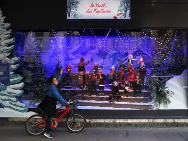 Seorang anak yang mengendarai sepeda berhenti untuk melihat etalase Natal di pusat perbelanjaan Printemps di Paris, Prancis, 22 November 2020. Deretan pusat perbelanjaan telah meluncurkan etalase Natal mereka meskipun masih tutup selama karantina wilayah kedua di seluruh Prancis. (Xinhua/Gao Jing)