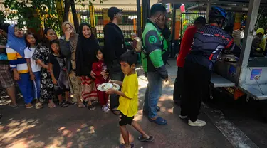 Warga antre mendapatkan sepiring nasi sayur dan lauk pauk saat pembagian makan siang gratis di wilayah Jati Padang, Pasar Minggu, Jakarta Selatan, Selasa (13/8/2024). (merdeka.com/Arie Basuki)