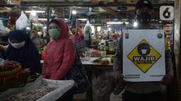Petugas Polres Jakarta Timur melakukan sosialisasi dan membagikan masker di Pasar Palmeriam, Matraman, Selasa (9/2/2021). Kegiatan itu dilakukan sebagai upaya meningkatkan kesadaran masyarakat akan pentingnya penerapan protokol kesehatan untuk menekan penyebaran Covid-19. (merdeka.com/Imam Buhori)