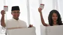 Anies Baswedan bersama anaknya menunjukan kertas suara sebelum memasukan ke kotak saat menggunakan hak pilihnya di TPS 28 Cilandak, Jakarta Selatan, Rabu (19/4). (Liputan6.com/Yoppy Renato)
