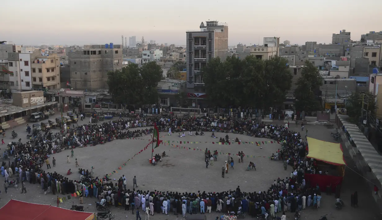 Orang-orang menonton turnamen gulat tradisional Sindhi Malakhra di kota pelabuhan Karachi, Pakistan pada Minggu (13/12/2020). Gulat kuno yang dimulai sejak 5.000 tahun lalu ini salah satu olahraga favorit di kalangan pria. (Photo by Asif HASSAN / AFP)