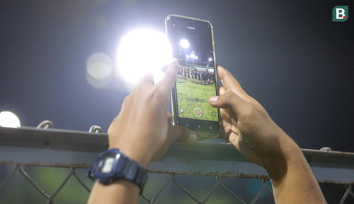 Seorang jurnalis tengah merekam latihan pemusatan latihan Timnas Indonesia U-20 yang berlangsung di Lapangan B, Senayan, Jakarta, Jumat (15/03/2024) malam. (Bola.com/Bagaskara Lazuardi)