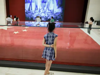 Seorang gadis melihat bendera nasional Tiongkok yang dikibarkan pada 1 Oktober 1949 di Lapangan Tiananmen di Museum Nasional China di Beijing (22/8/2019). Negara itu akan merayakan peringatan ke-70 berdirinya Pendirian Republik RakyatTiongkok pada tanggal 1 Oktober 2019. (AFP Photo/Wang Zhao)