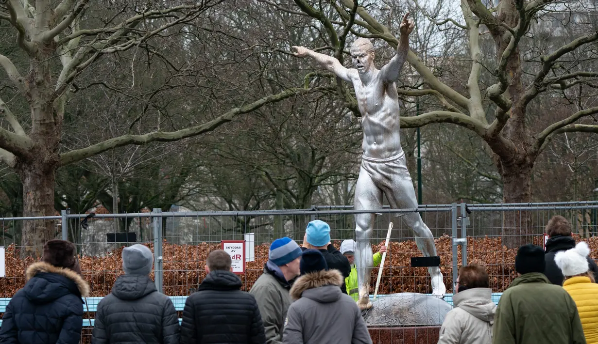 Warga menyaksikan patung Zlatan Ibrahimovic yang rusak, Malmo, Swedia, Minggu (22/12/2019). Perusakan patung yang terjadi untuk kesekian kali tersebut dilakukan fans Malmo karena kecewa sang idola membeli saham di klub rival, Hammarby. (Johan Nilsson/TT News Agency via AP)