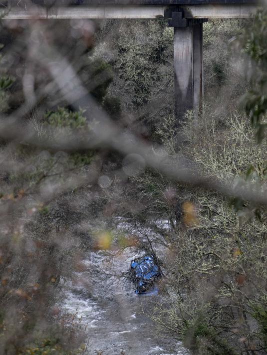 Bangkai bus terlihat di sungai Lerez setelah jatuh saat melintasi jembatan, menewaskan empat orang, di Cerdedo-Cotobade, Spanyol (25/12/2022). Kecelakaan itu terjadi pada 24 Desember malam di dekat Vigo dan perbatasan dengan Portugal. (AFP/Brais Lorenzo)