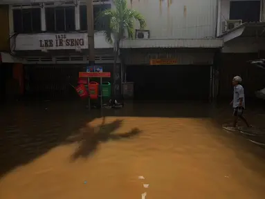 Warga melintas di depan pertokoan yang ada di kawasan Pasar Baru, Jakarta, Kamis (2/1/2020). Pasca banjir yang melanda sejumlah titik di Jakarta pada Rabu (1/1), aktivitas perniagaan di kawasan Pasar Baru masih terlihat sepi dan sebagian toko masih tutup. (Liputan6.com/Helmi Fithriansyah)