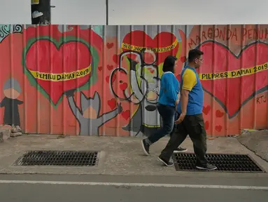 Pejalan kaki melintasi mural yang menghiasi tembok di kawasan Margonda, Depok, Sabtu (16/2). Gambar mural memiliki pesan agar masyarakat tetap damai dan berteman meski berbeda dalam memilih calon presiden dalam Pilpres 2019. (Liputan6.com/Herman Zakharia)