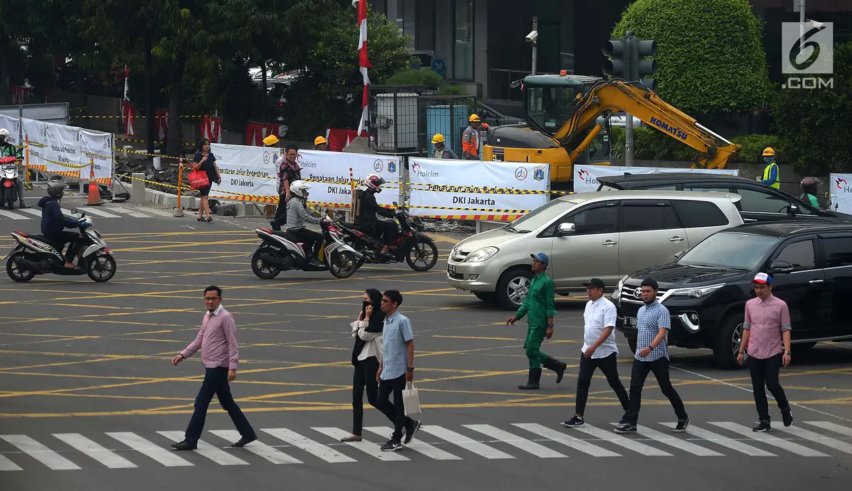 Warga menyeberang jalan dekat proyek pelebaran jalur khusus pejalan kaki atau pedestrian di kawasan Sarinah, Jakarta, Rabu (4/7). Pelebaran ini dilakukan untuk menyambut Asian Games 2018. (Merdeka.com/Imam Buhori)