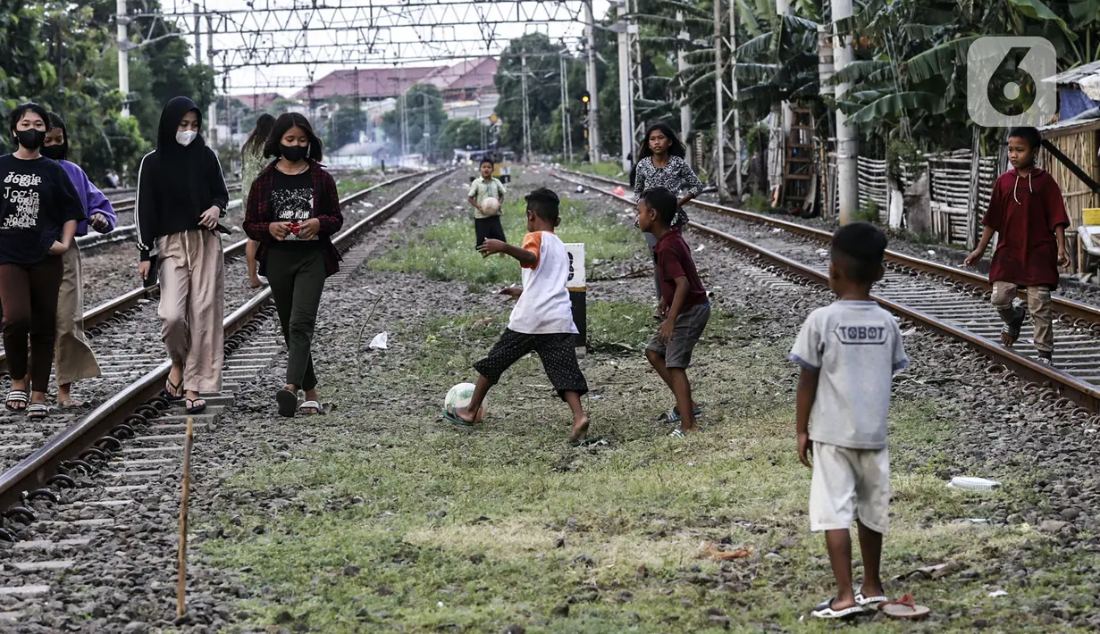 Anak-anak bermain bola di tengah perlintasan kereta api kawasan Ancol, Jakarta Utara, Kamis (19/5/2022). Data Kementerian Kesehatan pada 17 Mei 2022 mengungkapkan, enam orang meninggal karena diduga terjangkit hepatitis akut yang belum diketahui penyebabnya alias hepatitis misterius. (Liputan6.com/Johan Tallo)