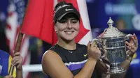 Petenis Kanada, Bianca Andreescu (19) tersenyum saat berpose dengan Piala AS Terbuka 2019 usai mengalahkan Serena Williams dari AS di final tunggal putri di New York (7/9/2019). Andreescu menang atas Serena 6-3, 7-5. (AP Photo/Charles Krupa)