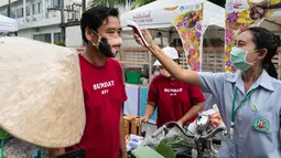 Seorang staf memeriksa suhu seorang penjual dalam festival kuliner di kota tua Phuket, Thailand (13/9/2020). Festival selama dua hari itu digelar untuk mendorong pariwisata dan perekonomian setempat. (Xinhua/Zhang Keren)