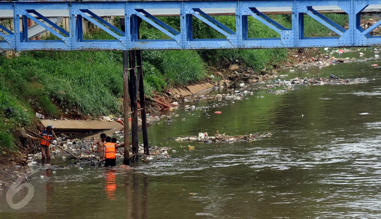Petugas berusaha mengangkuti ceceran sampah di pinggir Kali Ciliwung di sisi jalan Menteng Tenggulun, Jakarta, Kamis (22/12). Turunnya debit air Kali Ciliwung membuat ceceran sampah tersangkut. (Liputan6.com/Helmi Fithriansyah)