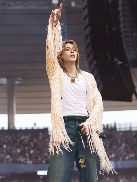 Jimin bergaya messy casual dengan sweater rajut wol putih gading, tanktop katun putih, dan ripped jeans. Ia juga mengenakan ikat pinggang kulit hitam dan sepasang sepatu bot kulit krem ​​bertali. [Dior]
