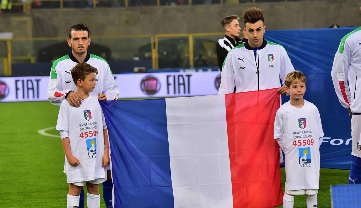 Pemain Italia, Stephan El Shaarawy (kanan) dan Alessandro Florenzi memegang bendera Prancis pada laga persahabatan melawan Rumania di Stadion Renato Dall'Ara, Bologna, Rabu (18/11/2015) dini hari WIB.  (AFP Photo/Giuseppe Cacace)