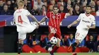 Aksi pemain Bayern, Javi Martinez (tengah) berusaha melewati adangan dua pemain Sevilla pada leg pertama Liga Champions di Sanchez Pizjuan stadium, Seville, (3/4/2018) waktu setempat. Beyern menang 2-1. (AP/Miguel Morenatti)