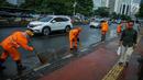Petugas Dinas Kebersihan membersihkan genangan air usai hujan di kawasan jalan Sudirman, Jakarta, Rabu (22/11). Buruknya sistem drainase membuat petugas membersihkan genangan setiap kali hujan, meski dengan peralatan seadanya. (Liputan6.com/Faizal Fanani)
