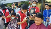 Para tukang cukur handal Persaudaraan Pemangkas Rambut Garut (PPRG) nampak asik memberikan pelayanan cukur gratis kepada 76 anak yatim dalam puncak perayaan HUT Bhayangkara di Garut. (Liputan6.com/Jayadi Supriadin)