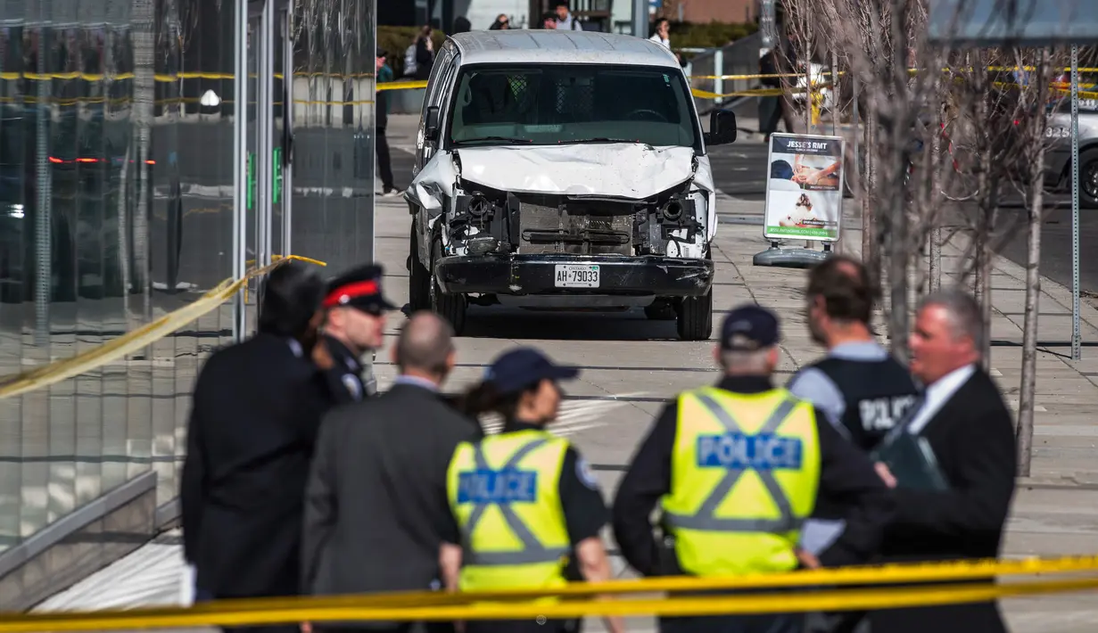 Aparat polisi berdiri dekat sebuah van yang menabrak para pejalan kaki di persimpangan utama di pinggiran utara Toronto, Kanada, Senin (23/4). Sembilan orang tewas dan 16 lainnya terluka dalam insiden itu. (Aaron Vincent Elkaim/The Canadian Press via AP)