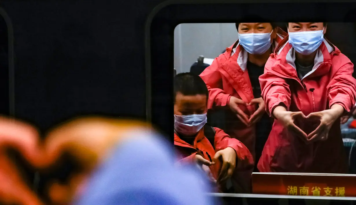 Staf medis dari Provinsi Hunan memberi isyarat ucapan selamat tinggal di dalam kereta di Stasiun Kereta Api Wuhan di Provinsi Hubei, China (17/3/2020). Beberapa tim bantuan medis  mulai meninggalkan Hubei ketika epidemi COVID-19 yang terkena dampak paling parah itu terus menurun. (Xinhua/Shen Bohan)