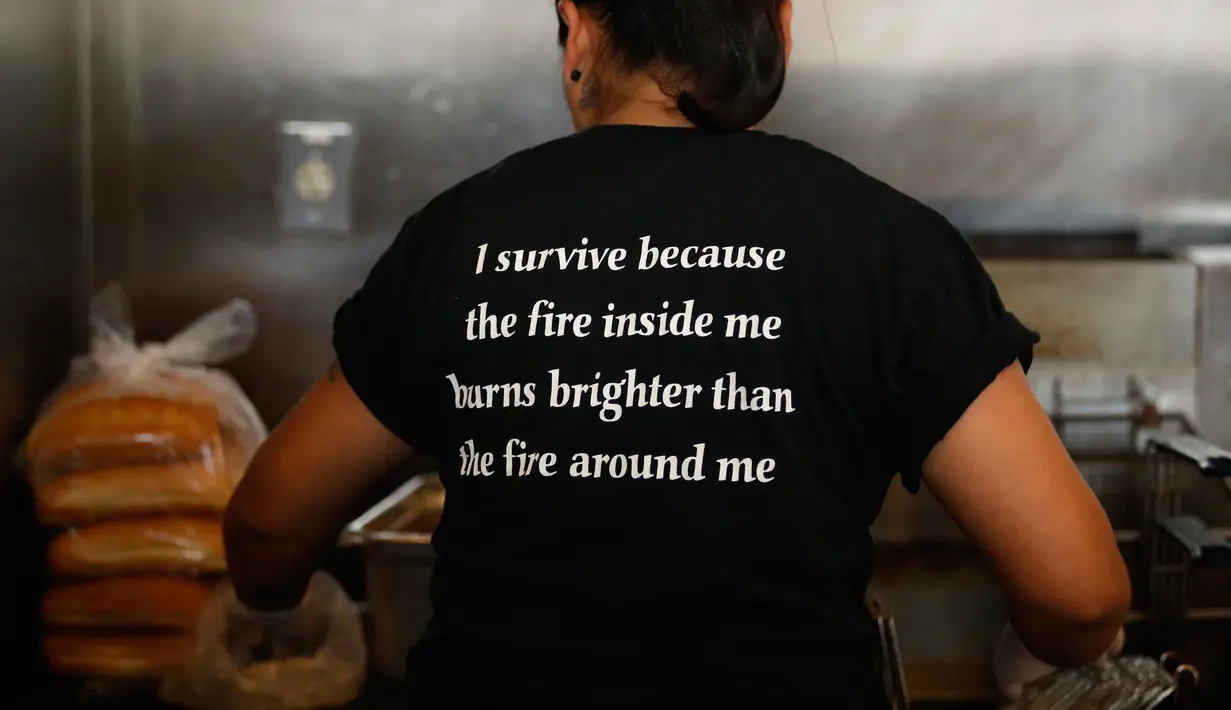 Yanet Rodriguez mengenakan kaus dengan kata-kata motivasi di dapur Homegirl Cafe, Los Angeles, Senin (16/7). Para mantan anggota geng ini sering berbagi cerita ke pengunjung tentang pengalaman mereka mendapatkan kehidupan yang lebih baik. (AP/Jae C. Hong)