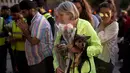 Seorang wanita bersama anjingnya sebelum meletakkan bunga di Albert Square, Manchester, Inggris, (23/5). Kejadian ini menyebabkan 22 orang tewas  dan melukai 119 lainnya. (AP Photo/Emilio Morenatti)