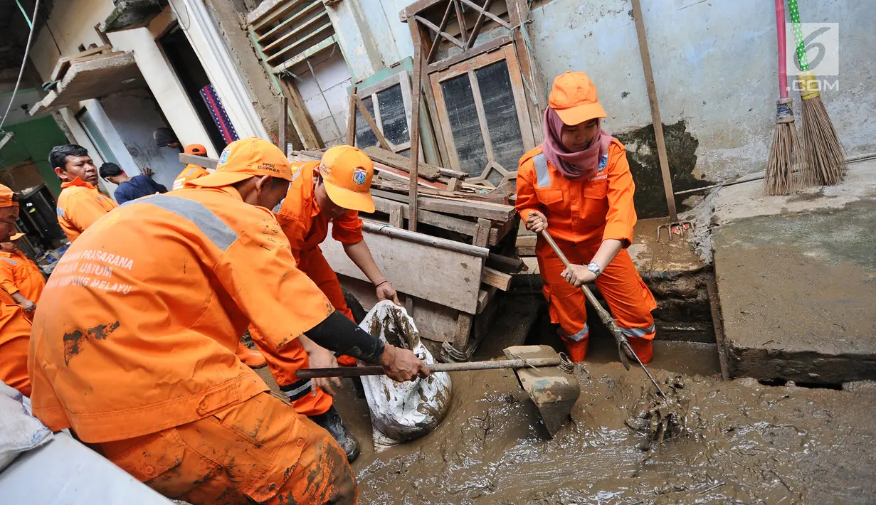Petugas PPSU Kelurahan Kampung Melayu Siti Hajar bersama rekan-rekannya membersihkan sisa lumpur akibat banjir yang melanda Kebon Pala, Jakarta, Kamis (25/4). (Liputan6.com/Herman Zakharia)