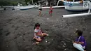 Anak-anak bermain pasir di kawasan wisata Pantai Amed, Bali, Selasa (5/12). Erupsi Gunung Agung membuat sektor pariwisata di Pulau Dewata, terutama wilayah Amed sepi dari wisatawan, baik lokal maupun mancanegara. (Liputan6.com/Immanuel Antonius)