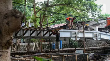 Pekerja menyelesaikan proyek pembangunan jembatan penghubung antarkampung di kawasan Pondok Pinang, Jakarta, Jumat (13/12/2019).  Jembatan yang menghubungkan permukiman di daerah Pondok Pinang dengan kawasan Bintaro tersebut ditargetkan rampung pada akhir Desember. (Liputan6.com/Faizal Fanani)