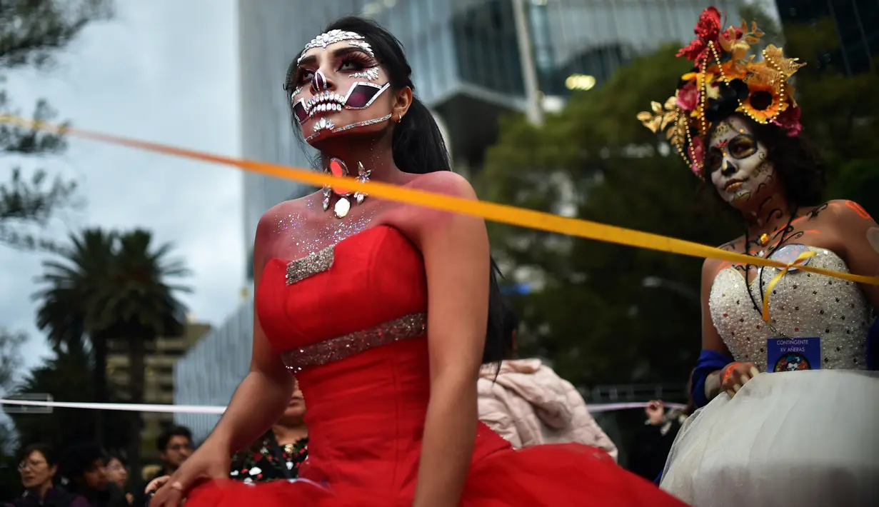 Orang-orang berpakaian seperti "Catrina" ambil bagian dalam parade catrinas atau Hari Orang Mati di Reforma Avenue, Mexico City, 21 Oktober 2018. La Catrina diciptakan oleh artis Meksiko Jose Guadalupe Posada. (RODRIGO ARANGUA/AFP)