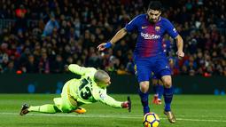 Pemain Barcelona, Luis Suarez berusaha menghindari kiper Deportivo La Coruna, Ruben Martinez pada pertandingan pekan ke-16 La Liga di Stadion Camp Nou, Senin (18/12). Barcelona unggul 4-0 tamunya La Coruna lewat dua gol Suarez. (AP/Manu Fernandez)